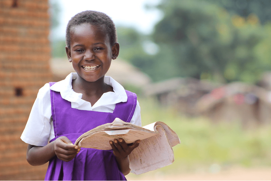 Smiling child holding papers for school